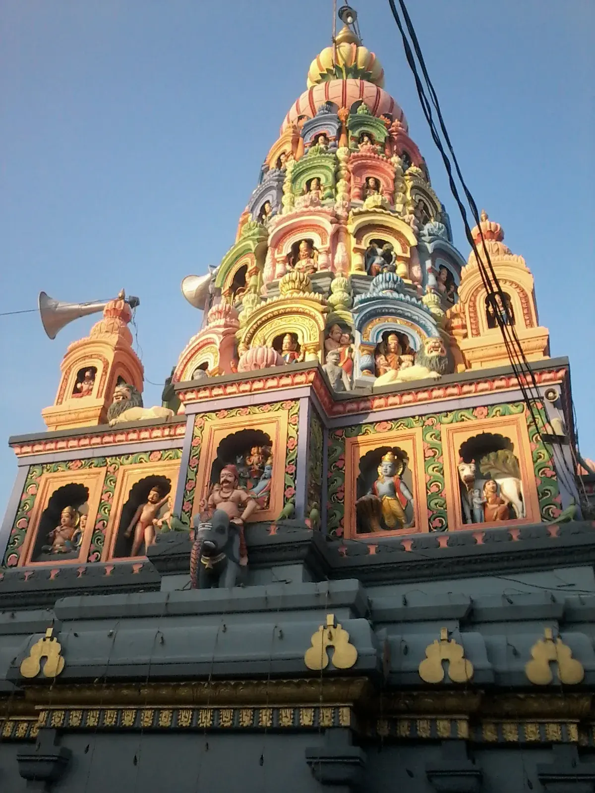 योगेश्वरी मंदिर का शिखर नीचे से देखा हुआ; इसके स्तर चटख रंगों में रंगे हैं और प्रत्येक कोनाड़े में एक मूर्ति है।