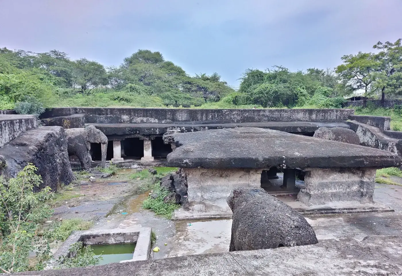 सपाट भूमि में उत्कीर्ण लेणी समूह, जिसके स्तंभयुक्त मंडप शिला में ही खोदे गए हैं; प्रवेश पर बड़े क्षरित उत्कीर्ण हाथी खड़े हैं और सम्मुख शिला में कटा जलकुंड है।