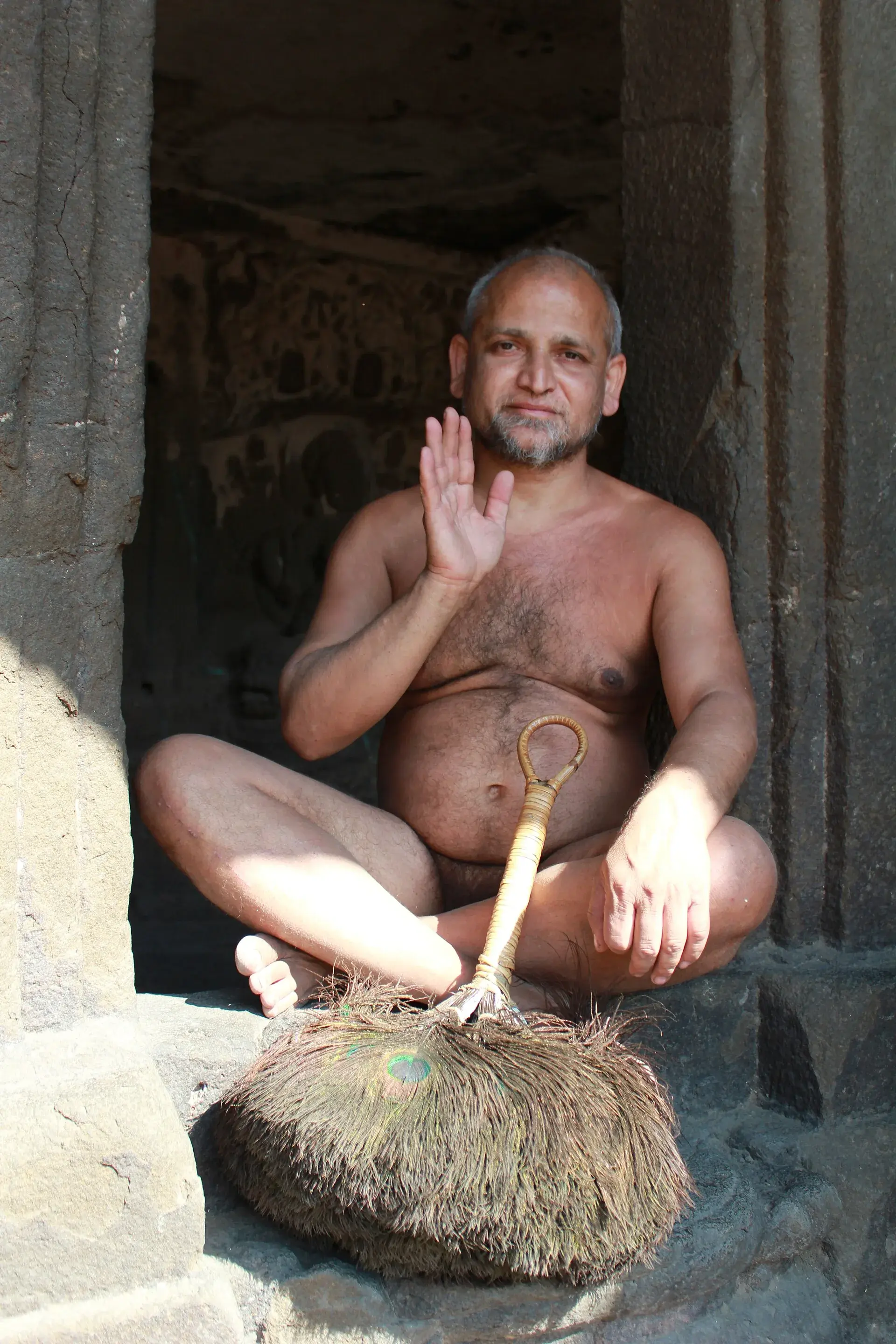 एलोऱ्यातील तेहेतिसाव्या जैन लेणीच्या दारात जमिनीवर विराजमान दिगंबर मुनी, वस्त्रहीन, एक हात आशीर्वादाच्या मुद्रेत उंचावलेला आणि शेजारी मोरपिसांची पिच्छी ठेवलेली.