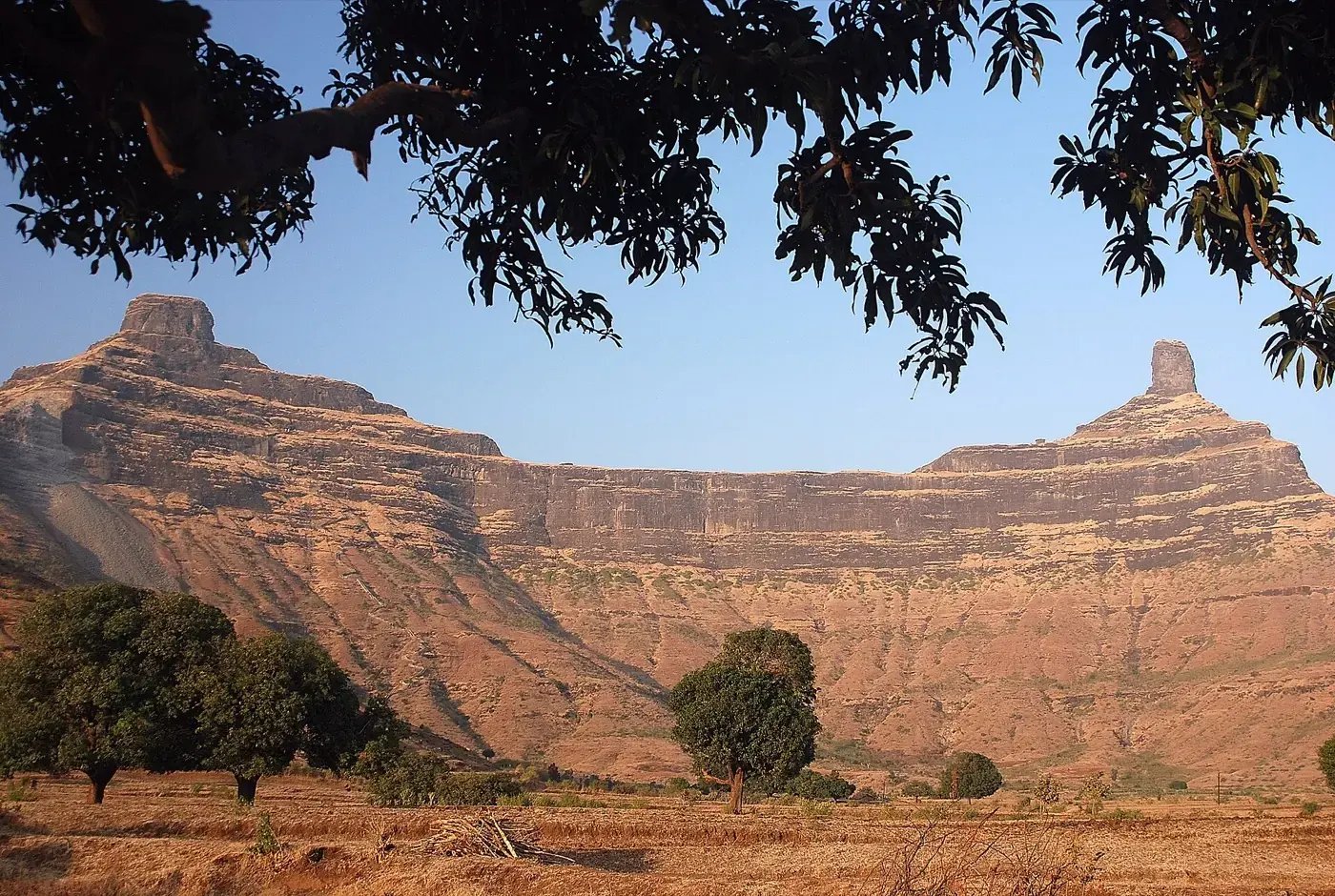 Two rock pinnacles rising from a broad plateau in the Western Ghats, joined by a saddle of land between them.